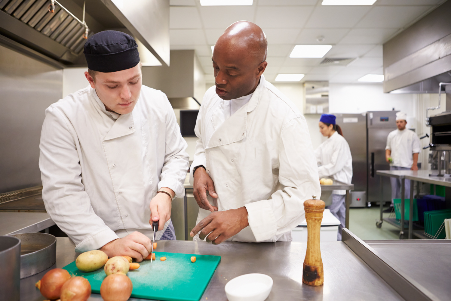 Teacher Helping Students Training To Work In Catering